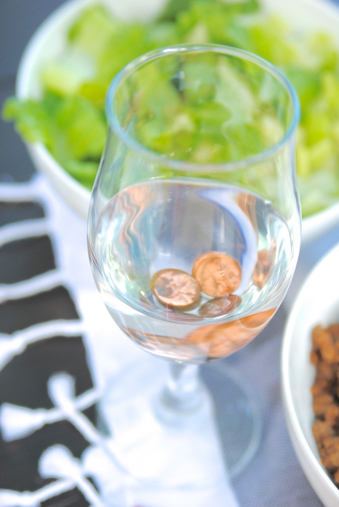 A fully glass of water with pennies at the bottom