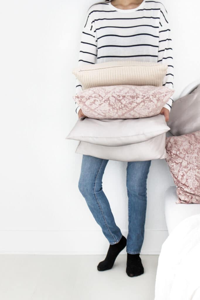 woman organizing stack of pillows and linens