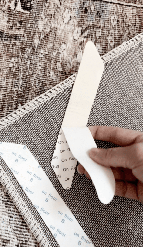 removing the backing of a stick-on rug gripper on the back of a rug